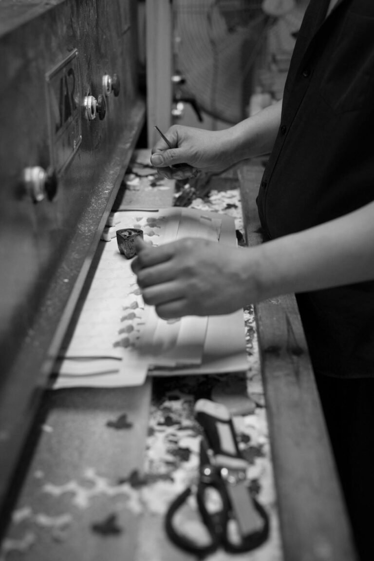 Black and white close-up of a craftsman working in a workshop with a focus on hands and tools.